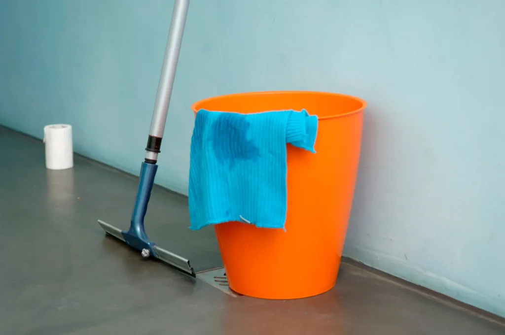 Mop, bucket, and squeegee beside a floor drain